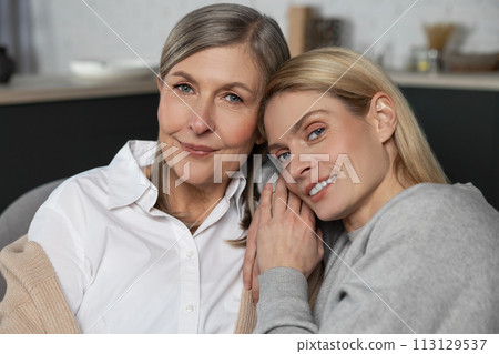 Mature mother and her adult daughter hugging and talking 113129537