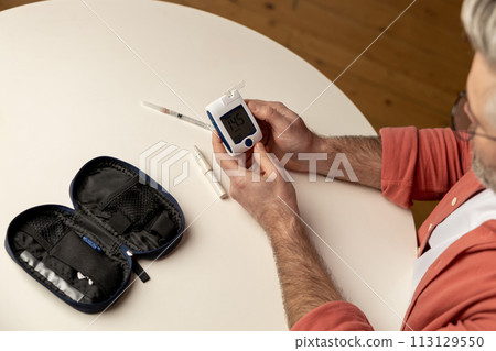 Unhealthy diabetic man checking level of sugar in blood with glucometer 113129550
