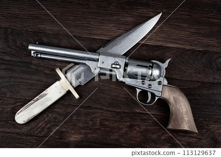 Old West Revolver with bowie knife on wooden deck. Old West Revolver with bowie knife on wooden deck. 113129637