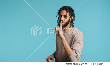 Middle Eastern man pretending to fight, throwing punches, holding defensive guard. BIPOC martial artist person mock boxing, holding combat stance, exercising in blue studio background, camera A 113130488