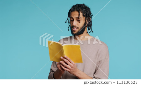 Middle Eastern man reading book from publisher aloud, telling story, enjoying hobby. BIPOC person narrating literature novel, doing critique essay, isolated over studio background, camera B Middle Eastern man reading book from publisher aloud, telling story, enjoying hobby. BIPOC person narrating literature novel, doing critique essay, isolated over studio background, camera B 113130525