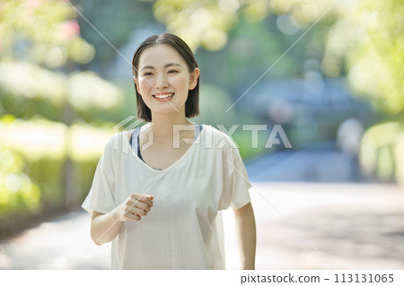 Smiling young woman running in sportswear Smiling young woman running in sportswear 113131065