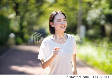 Smiling young woman running in sportswear 113131811