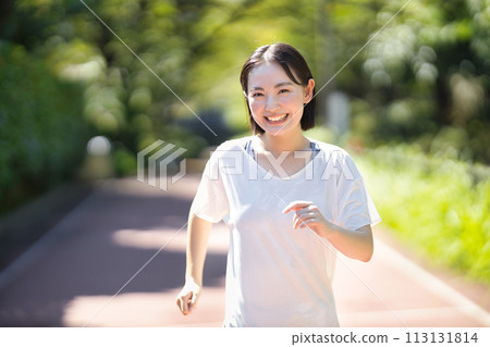 Smiling young woman running in sportswear 113131814