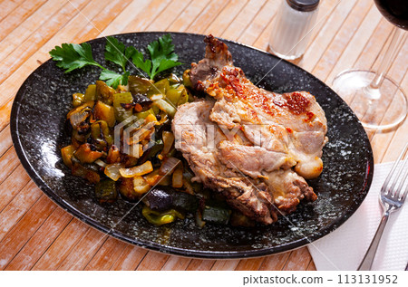Roasted pork loin served with garnish of baked vegetables 113131952