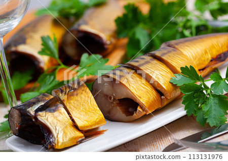 Smoked mackerel cut into pieces with parsley on a table Smoked mackerel cut into pieces with parsley on a table 113131976