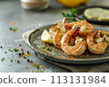 Char-grilled shrimps seasoned with herbs on a rustic ceramic plate, adorned with a wedge of lemon, on a gray 113131984