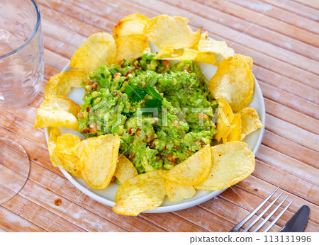 Beer snacks are laid out on plate - chips and portion of thick pasta sauce guacamole Beer snacks are laid out on plate - chips and portion of thick pasta sauce guacamole 113131996