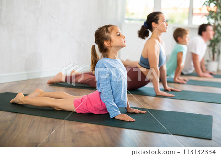 Little girl with family practicing yoga in studio 113132334