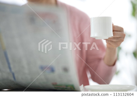 中年婦女一邊喝咖啡一邊看報紙 113132604