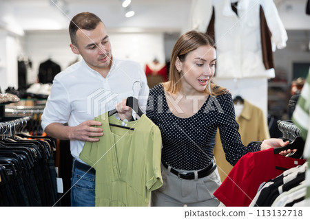 Man with wife participate in inspection of goods, help determine choice of dress Man with wife participate in inspection of goods, help determine choice of dress 113132718