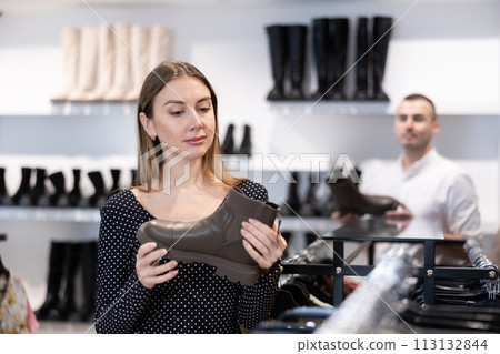 Young woman choosing boots in shoe store Young woman choosing boots in shoe store 113132844