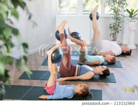 Children and parents practice yoga and Pilates using soft ball in gym Children and parents practice yoga and Pilates using soft ball in gym 113132969