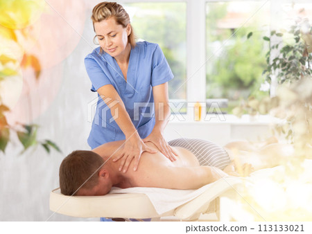 the client lies while the woman gives a massage 113133021