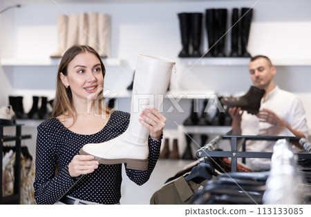 Young woman choosing boots in shoe store 113133085