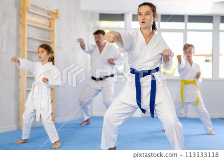 Woman practicing kata routine during family training at karate class Woman practicing kata routine during family training at karate class 113133118