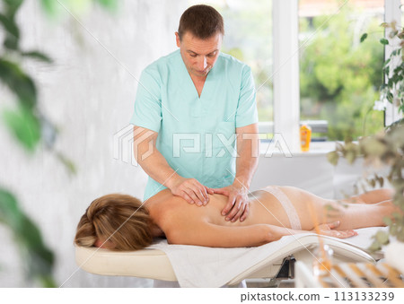 Woman enjoys back massage during spa treatments at cosmetology center 113133239