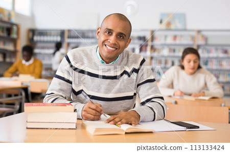 Young adult man studying in public library 113133424
