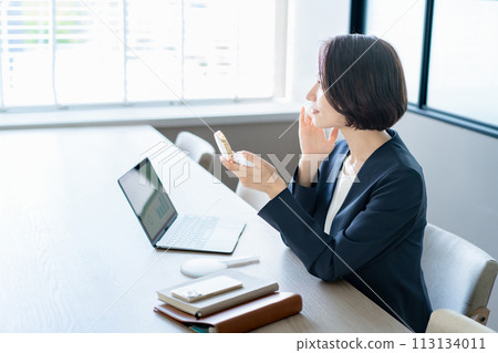 A woman checking her skin in the office 113134011