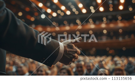 Man in a suit speaks to crowd with powerful gestures at event Man in a suit speaks to crowd with powerful gestures at event 113135656