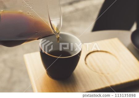 Coffee on a wooden tray poured from a glass container Coffee on a wooden tray poured from a glass container 113135898