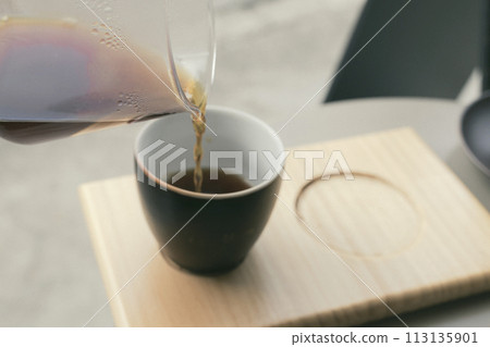 Coffee on a wooden tray poured from a glass container Coffee on a wooden tray poured from a glass container 113135901