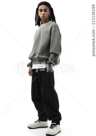 Man in sweater and black pants poses with arm gesture on white background Man in sweater and black pants poses with arm gesture on white background 113136199