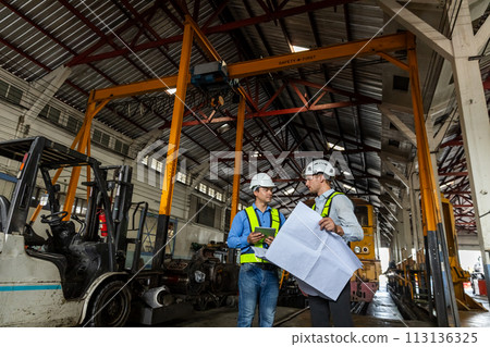 Railway technician engineer wearing safety uniform and safety helmet holding tablet and blueprint. Railway technician engineer wearing safety uniform and safety helmet holding tablet and blueprint. 113136325