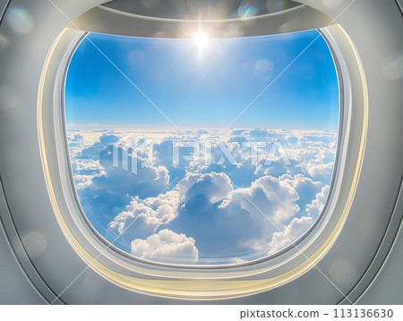 A breathtaking view of a cloud landscape seen from an airplane window, with the sun shining brightly above 113136630