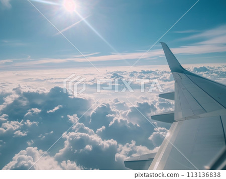 View from an airplane's wing as it glides over a sea of clouds, with the sun casting a soft light across the sky View from an airplane's wing as it glides over a sea of clouds, with the sun casting a soft light across the sky 113136838