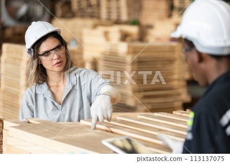 woman wearing safety uniform and hard hat working quality inspection of wooden products at workshop woman wearing safety uniform and hard hat working quality inspection of wooden products at workshop 113137075