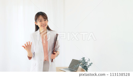 Middle-aged woman in a white coat explaining while looking at the camera Middle-aged woman in a white coat explaining while looking at the camera 113138528