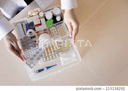 Closeup female hand placing medicament domestic first aid kit. Storage organization emergency supply Closeup female hand placing medicament domestic first aid kit. Storage organization emergency supply 113139292