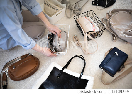 A young woman puts various women's handbags for storage in her home wardrobe. Accessories and bags. A young woman puts various women's handbags for storage in her home wardrobe. Accessories and bags. 113139299