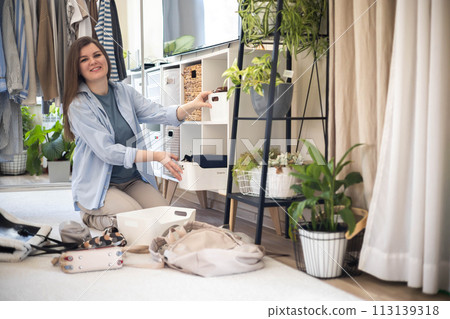 A young woman puts various women's handbags for storage in her home wardrobe. Accessories and bags. A young woman puts various women's handbags for storage in her home wardrobe. Accessories and bags. 113139318