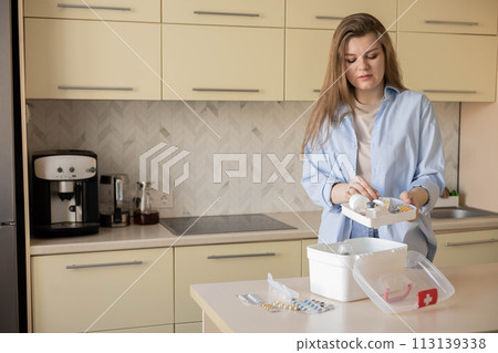 Female housewife checking medicines at domestic first aid kit neatly placing storage organization 113139338