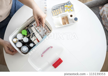 Closeup female hand placing medicament domestic first aid kit. Storage organization emergency supply Closeup female hand placing medicament domestic first aid kit. Storage organization emergency supply 113139353