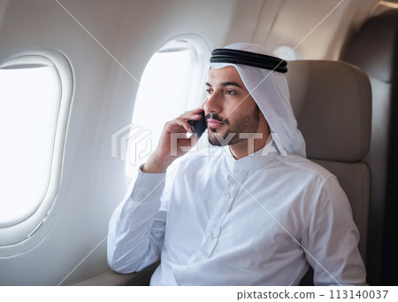 Arab businessman with cell phone while sitting in private jet airplane. Confident entrepreneur flying private jet, successful business 113140037