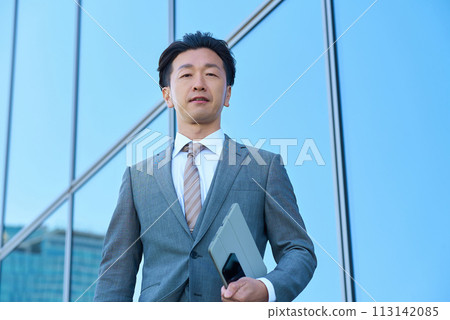 Businessman in a suit looking up at the sky outdoors 113142085