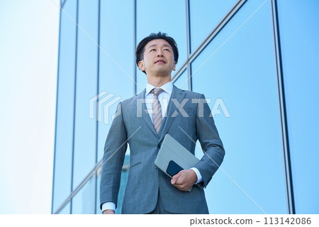 Businessman in a suit looking up at the sky outdoors 113142086