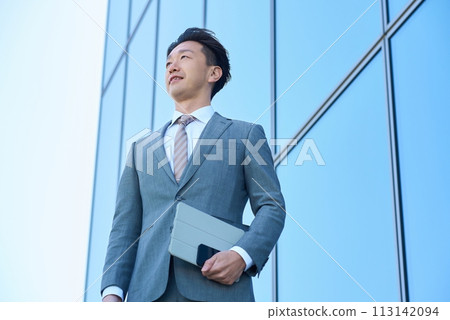 Businessman in a suit looking up at the sky outdoors 113142094