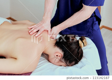 Woman lying face down on massage table, young Caucasian woman undergoing physiotherapy treatments. Woman lying face down on massage table, young Caucasian woman undergoing physiotherapy treatments. 113142187