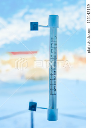 An outdoor thermometer is attached with adhesive tape to window glass outside, on scale of 20 degrees below zero Celsius. An outdoor thermometer is attached with adhesive tape to window glass outside, on scale of 20 degrees below zero Celsius. 113142189