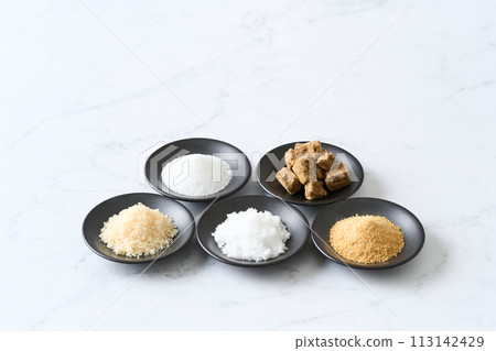 Various types of sugar on a small plate: granulated sugar, brown sugar, white sugar, beet sugar, and brown sugar. 113142429
