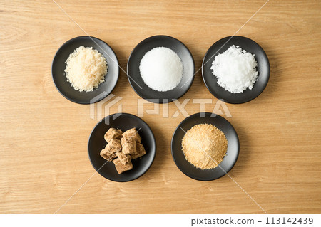 Various types of sugar on a small plate: granulated sugar, brown sugar, white sugar, beet sugar, and brown sugar. 113142439