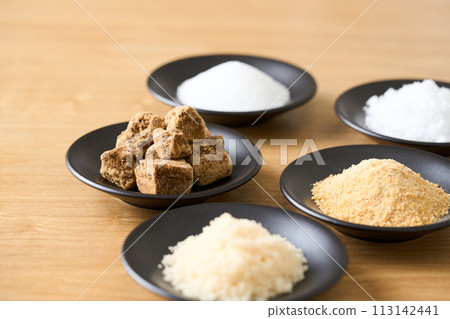 Various types of sugar on a small plate: granulated sugar, brown sugar, white sugar, beet sugar, and brown sugar. 113142441