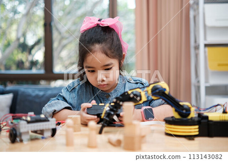 A young girl is playing with a remote control a robot A young girl is playing with a remote control a robot 113143082