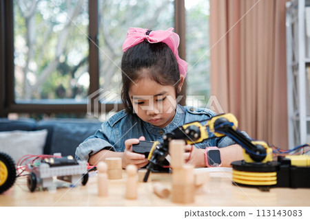 A young girl is playing with a remote control a robot 113143083