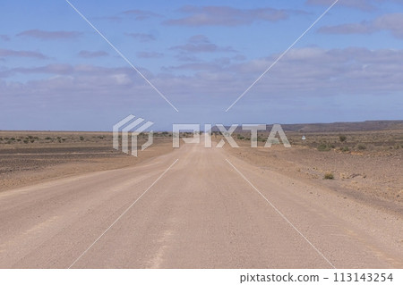 Panoramic picture over a gravel road through the desert like steppe in southern Namibia under a blue sky Panoramic picture over a gravel road through the desert like steppe in southern Namibia under a blue sky 113143254