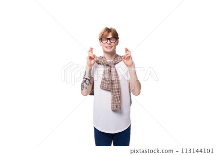 stylish red-haired guy in glasses and a plaid shirt crossed his fingers on a studio background 113144101